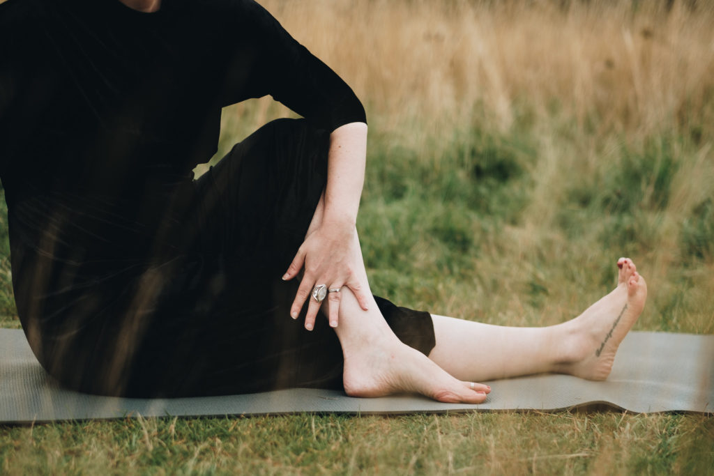 Close up image of a woman in a seated twist outside