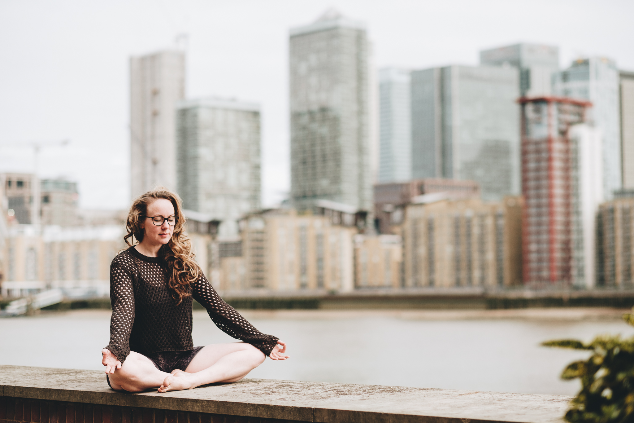 woman seated in sukhasana with london city behind her