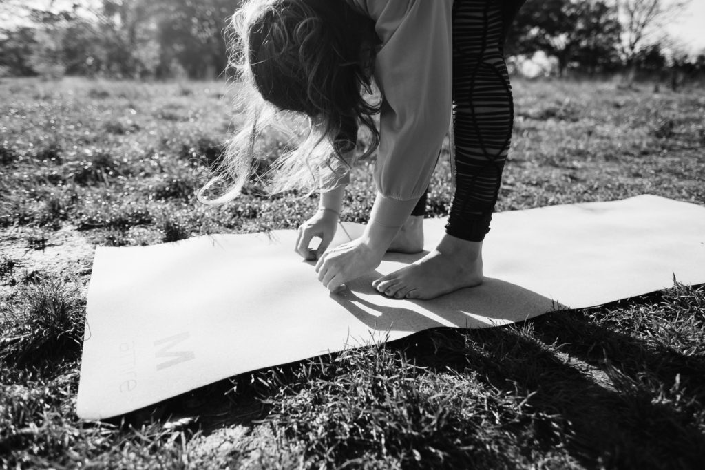 Black and white image of a woman in a forward fold on a yoga mat